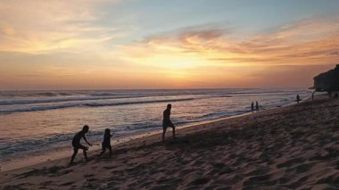 Baba ve oğlunun güzel bir günbatımında kumsalda koşup oynadığı bir video.