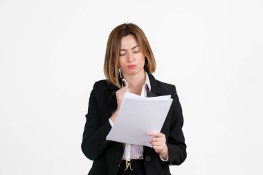 Siyah takım elbiseli düşünceli çekici bir iş kadını elindeki belgeleri beyaza izole etmiş.