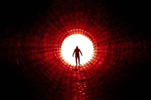 Büyük bir tünelin sonunda ışığa doğru yürüyen bir adamın silüeti. Kaçış, çıkış, özgürlük, klinik ölüm kavramı — Stok fotoğraf