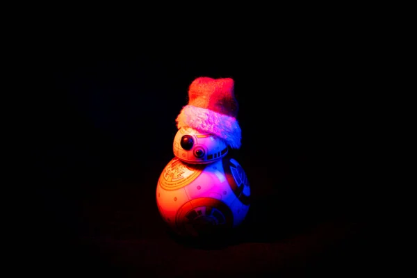 Incantevole droide BB-8 di Star Wars, indossando un cappello di Natale su sfondo scuro illuminato da luci colorate — Foto Stock