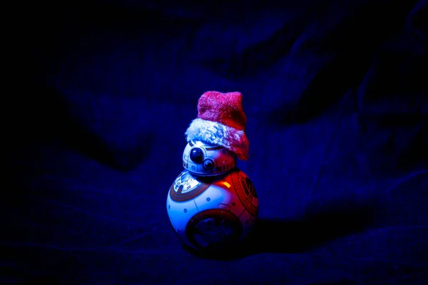 Incantevole droide BB-8 di Star Wars, indossando un cappello di Natale su sfondo scuro illuminato da luci colorate — Foto Stock