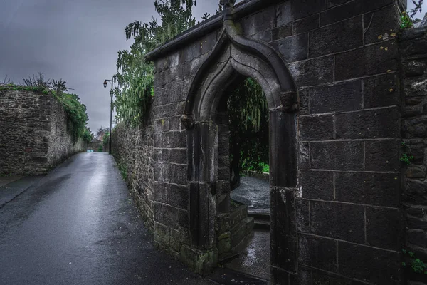 KILKENNY, IRELAND, DECEMBER 23, 2018: Spooky old stone and very wet entrance gate of a graveyard with mold and lichen growing. Concept of desolation and damage. — Stock Photo, Image