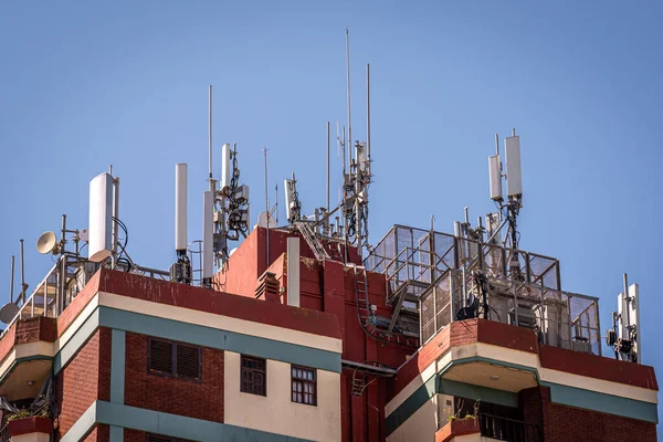 Antenas de la estación base del teléfono móvil colocadas sobre los tejados de un edificio Imágenes De Stock Sin Royalties Gratis