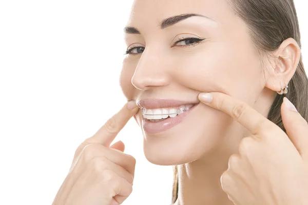 Hermosa chica sonriente con retenedor para los dientes apuntando a su s — Foto de Stock