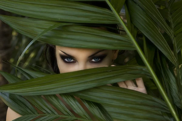 Sexy beautiful woman hiding behind the palm leaves. Beautiful st — Stock Photo, Image