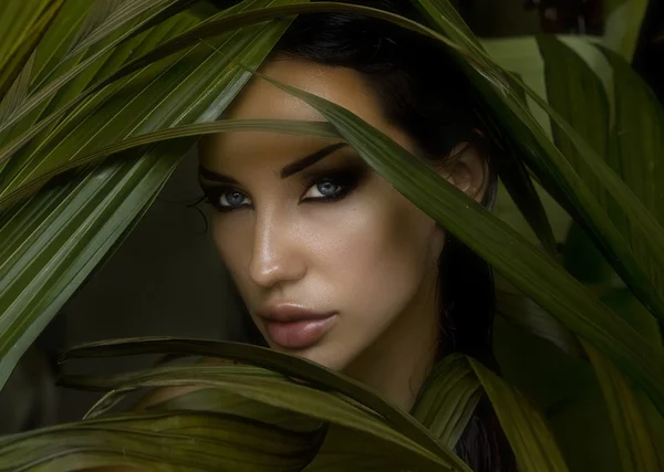 Sexy beautiful woman hiding behind the palm leaves. Beautiful st — Stock Photo, Image