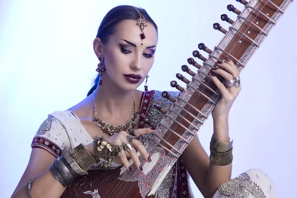 Mooie Indiase vrouw in sari met oosterse sieraden spelen de — Stockfoto