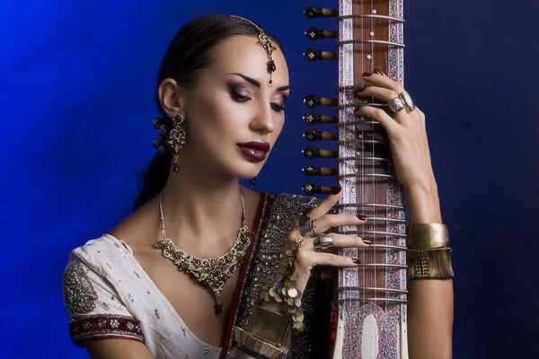 Schöne indische Frau in Sari mit orientalischem Schmuck spielt die — Stockfoto