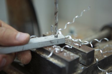 Man drilling in Steel Plate with Bench Drill. Close-up Electric
