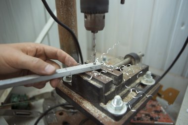 Man drilling in Steel Plate with Bench Drill. Close-up Electric