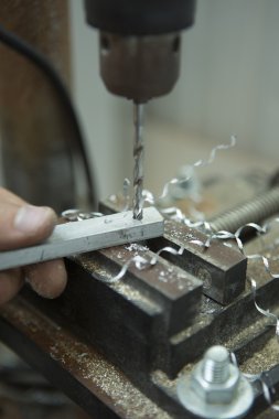 Man drilling in Steel Plate with Bench Drill. Close-up Electric