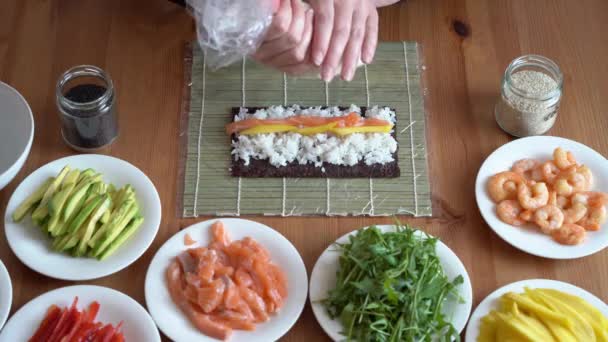 젊은 여자는 집에서 신선 한 재료로 초밥을 준비 한다. 나무 탁자 위 에서. — 비디오