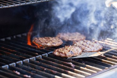 Izgarada hamburger için et pişiriyorum. Izgaradan alevler yükseliyor.