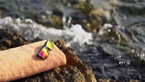 Serviette orange et lunettes de soleil posées sur un rocher près de la mer d'Istrie — Video