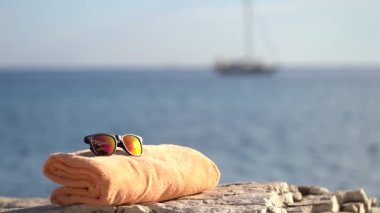 Turuncu havlu ve güneş gözlüğü Istrian Denizi 'nin yakınındaki bir kayanın üzerinde duruyordu.