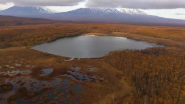 4k drone görüntüsü. Göl kenarına doğru giden kameranın havadan görüntüsü. Günbatımında Kamçatka Yarımadası 'nın güzel akşam volkanik manzarası: Avachinskaya volkanlarının sonbahar manzarası