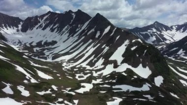 Kamçatka yarımadasındaki dağ zincirinin havadan görünüşü. 4K görüntü, dramatik hava görüntüsü. Temmuz 'da karlı dağlar
