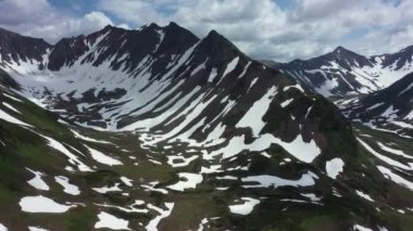 Kamçatka yarımadasındaki dağ zincirinin havadan görünüşü. 4K görüntü, dramatik hava görüntüsü. Temmuz 'da karlı dağlar