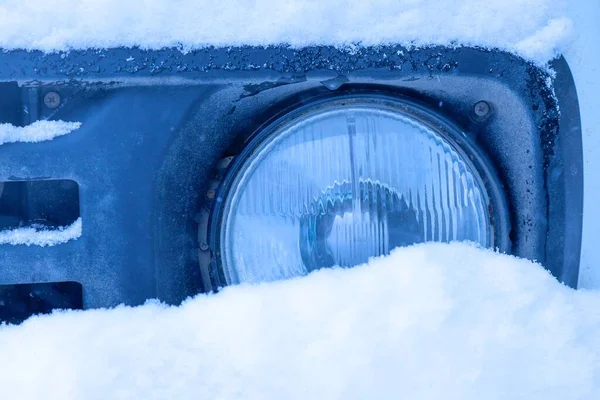 Bir kış fırtınasında, SUV karla kaplıydı. Arabanın karla kaplı kısmı (far) görünür.