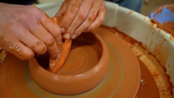 木製のスクレーパーとスポンジを使って土鉢を彫刻する職人の陶芸家 クローズアップ — ストック動画
