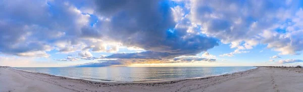 Akşam deniz kenarına düşer, güneş ufuktan batar. Kumda insan ayak izleri görülebilir. Mavi dramatik bulutlar Karadeniz 'in su yüzeyinde alçaktan süzülür (Deniz manzarası))