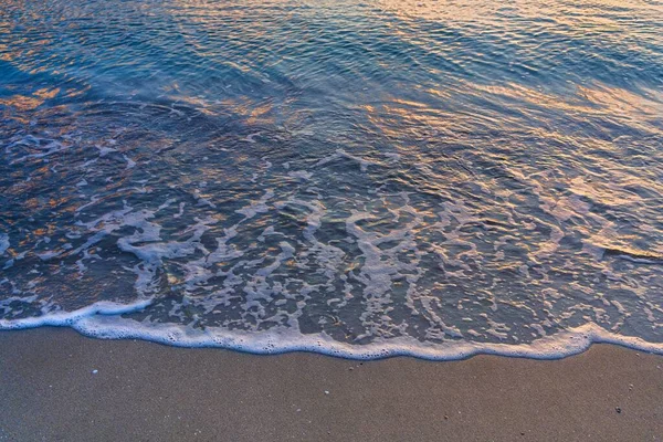 Deniz kumlu sahilin bir parçası. Dalga kum ve köpüklerin üzerinde yuvarlanır (Doğal zemin)