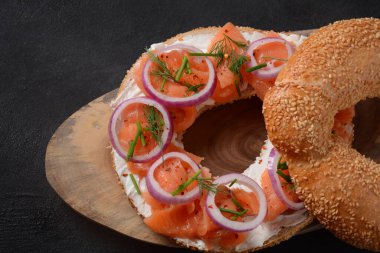 Somon, krem peynir, salatalık ve soğanlı simit sandviç.