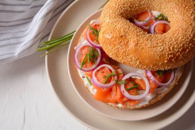 Somon, krem peynir, salatalık ve soğanlı simit sandviç.