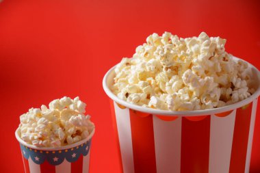 Kırmızı arka planda lezzetli patlamış mısır kovaları. Dökülmüş patlamış mısır 