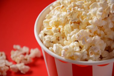 Kırmızı arka planda lezzetli patlamış mısır kovaları. Dökülmüş patlamış mısır 