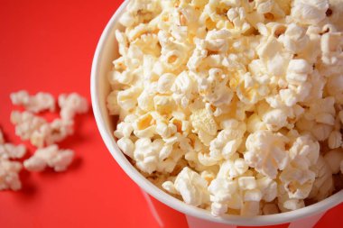 Kırmızı arka planda lezzetli patlamış mısır kovaları. Dökülmüş patlamış mısır 