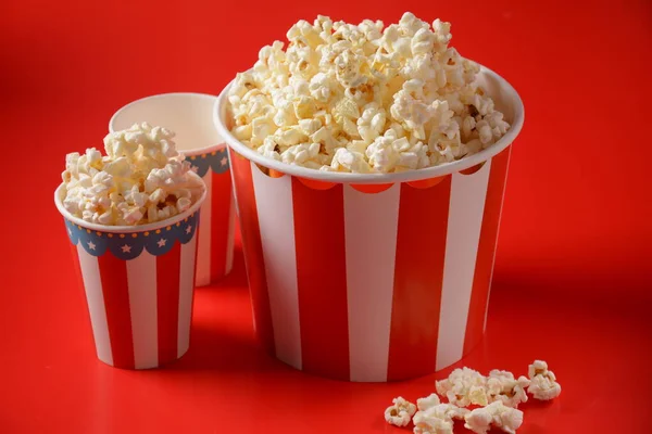 Kbelíky Lahodným Popcornem Červeném Pozadí Rozlitý Popcorn — Stock fotografie