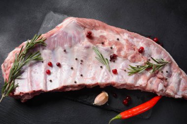 Tam çiğ domuz pirzolası. Taze domuz eti ve malzemeler: esmer arka planda baharatlar, tuz ve biberiye