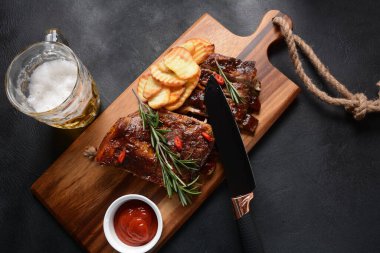 Barbekü soslu ızgara domuz pirzolası ve balda karamelize edilmiş. Tahta bir tahtanın üzerinde biraya lezzetli atıştırmalıklar. Bıçaklı ızgara domuz kaburgası, arka planda baharatlar.