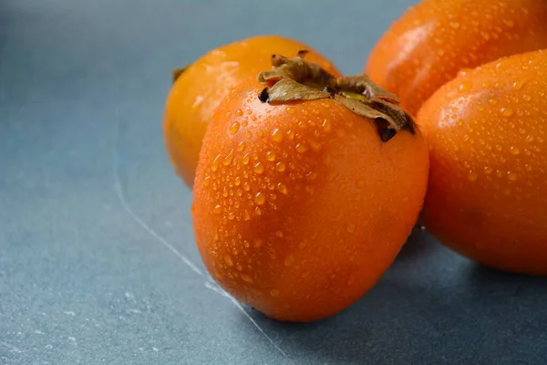 Tre Mogna Persimon Blå Bakgrund Läcker Färsk Persimon Frukt — Stockfoto