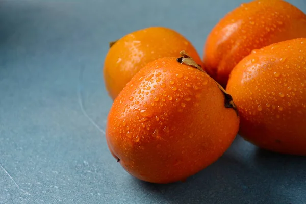 Tre Mogna Persimon Blå Bakgrund Läcker Färsk Persimon Frukt — Stockfoto