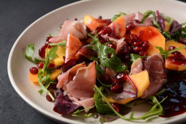 Pastırma, hurma, ıspanak, roka, marul yaprağı, nar tohumu ve bal soslu salata.