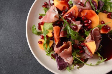 Pastırma, hurma, ıspanak, roka, marul yaprağı, nar tohumu ve bal soslu salata.