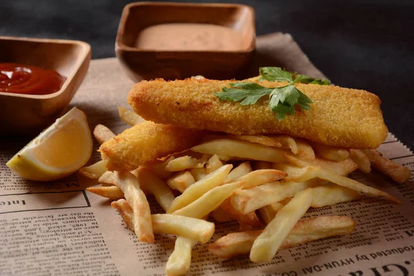 Traditional English Food - Fish and Chips. Fried fish filets and crispy French fries served with ketchup and homemade tarter sauce.