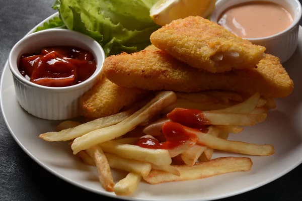 Traditional English Food - Fish and Chips. Fried fish filets and crispy French fries served with ketchup and homemade tarter sauce.