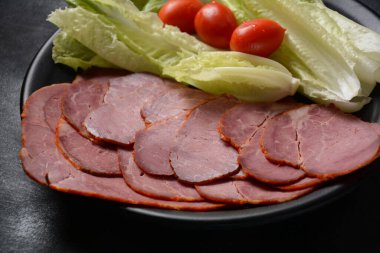 Vişneli domatesli füme biftek ve siyah tabakta marul.