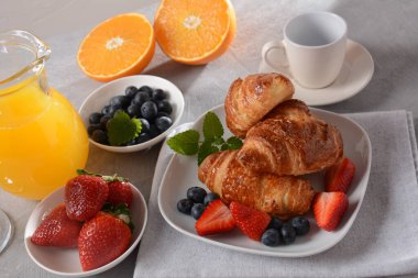 Lezzetli bir kahvaltı. Kruvasan, taze ve kurutulmuş meyve, taze meyve suyu.