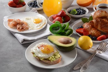 Sağlıklı kahvaltı. Avokado ve yumurtalı tost, pastırma ve yumurta, taze ve kuru meyve, taze meyve suyu