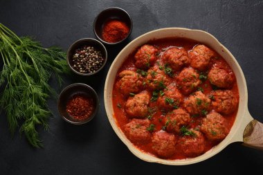 Boulettes de Poisson, Domates soslu kızarmış balık köfteleri beton bir masada malzemelerle birlikte.