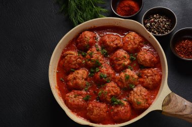 Boulettes de Poisson, Domates soslu kızarmış balık köfteleri beton bir masada malzemelerle birlikte.
