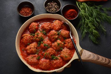Boulettes de Poisson, Domates soslu kızarmış balık köfteleri beton bir masada malzemelerle birlikte.