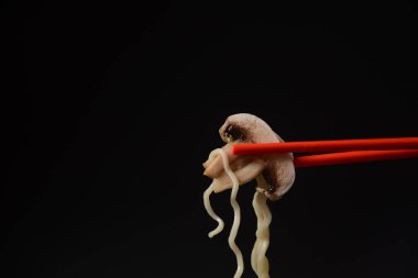 Çubuklar koyu arkaplandaki lezzetli erişteleri toplamak için kullanılır. Geleneksel Asya yemeği, abur cubur konsepti.