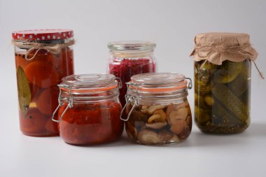 Ev yapımı sebze turşusu kavanozları: salatalık, domates, ballı tarımsal mantarlar, beyaz arka planda. Terbiye edilmiş ve mayalanmış yiyecekler. Fermente edilmiş vejetaryen gıda konsepti.