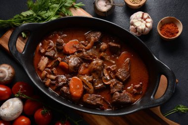 Tavada Bourguignon bifteği. Kırmızı şarap, havuç, soğan, sarımsak, bir buket garni ve inci soğan, mantar ve pastırmayla süslenmiş güveç. Fransız mutfağı. Burgundy 'den bölgesel tarif.