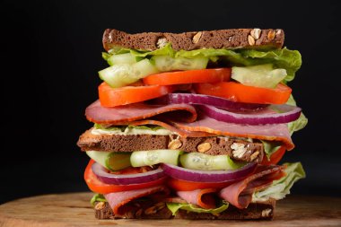 Füme biftekli sandviç, kırmızı soğan, salatalık, domates, marul ve tam tahıllı ekmek. Etli lezzetli, sağlıklı öğle yemeği.